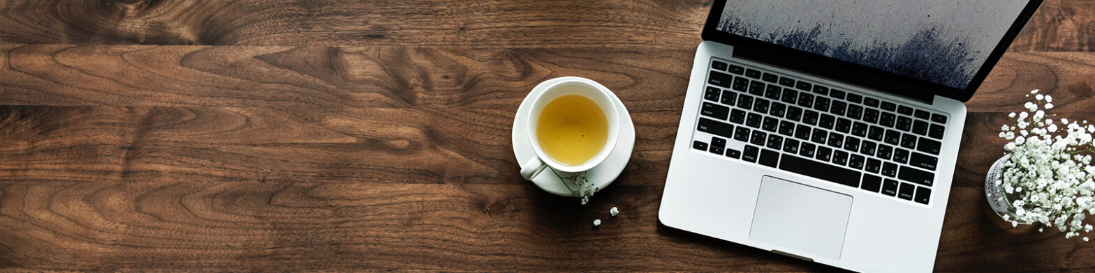 A laptop and a cup of tea on a desk