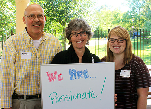 Three people with a white board that says We Are Passionate