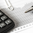 Calculator, pen, paper clip and financial chart