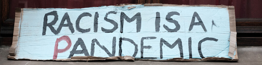 Street protest sign with the message "Racism is a Pandemic"