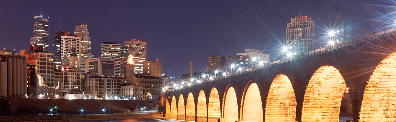 View of the Stone Arch Bridge leading towards the Minneapolis skyline at night