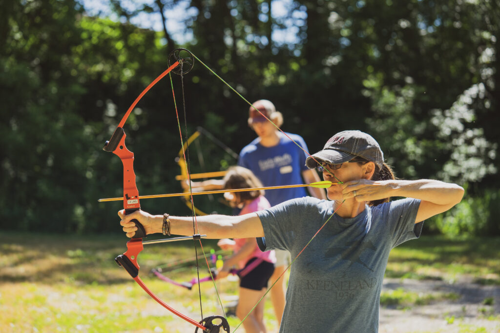 A woman draws a bow and arrow in an archery class.