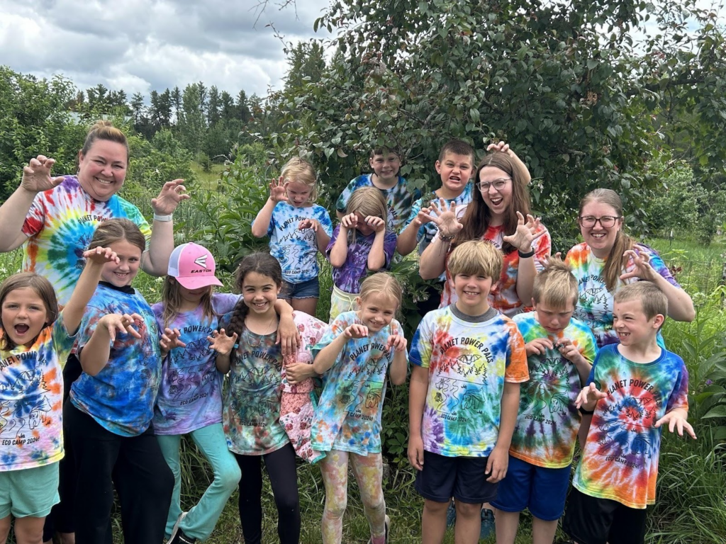 A group of children and adults pose in tie-dye t-shirts.